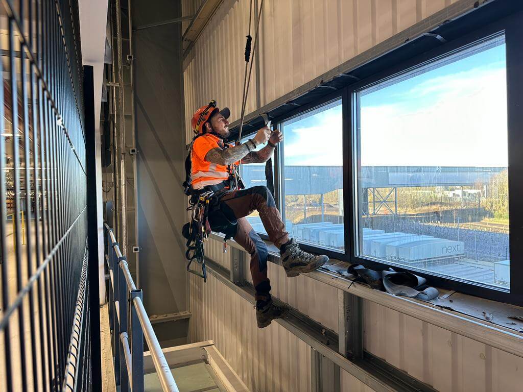 A man is hanging from a window on the building's facade.
