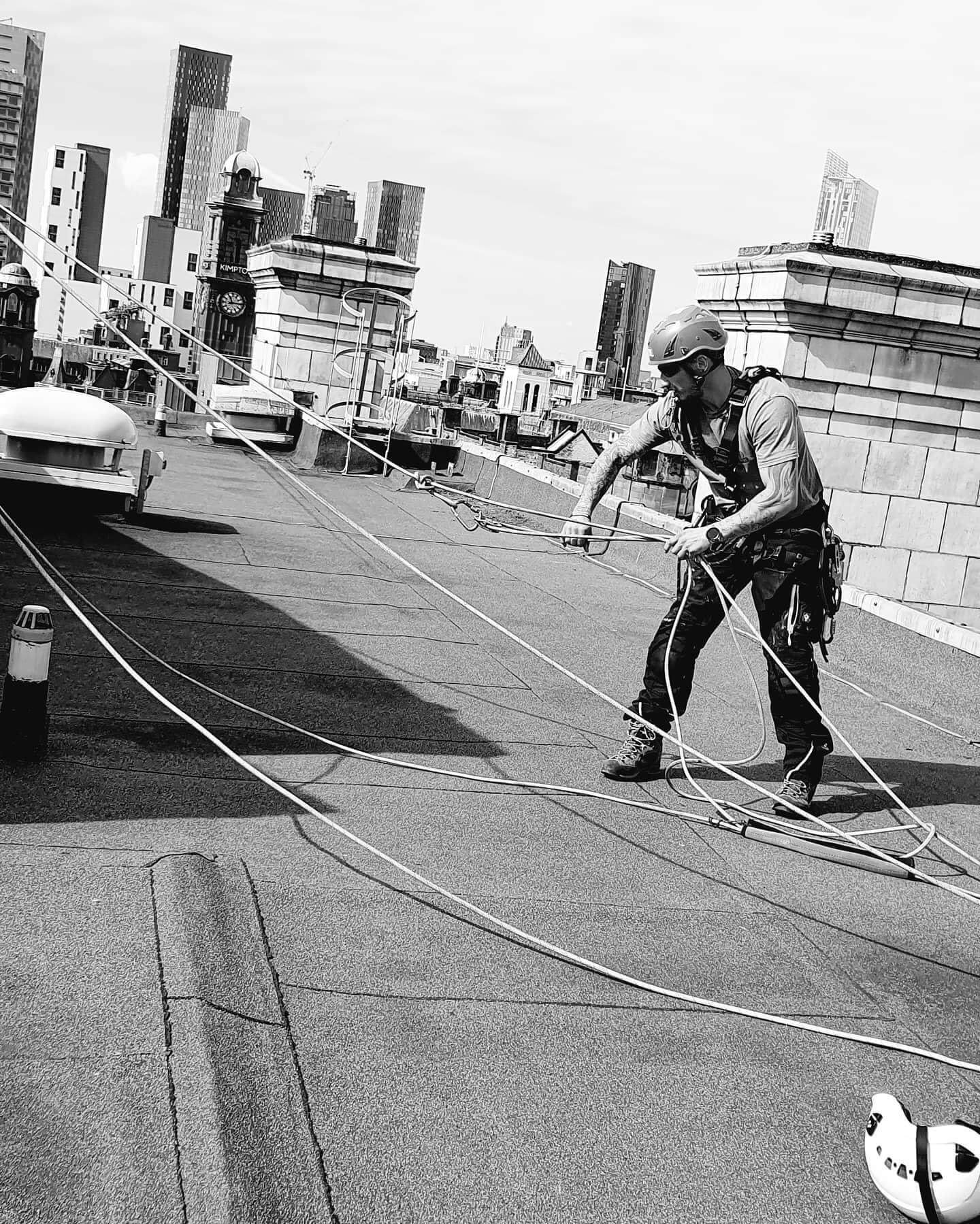 Black and white photo of a man performing building maintenance on a roof.