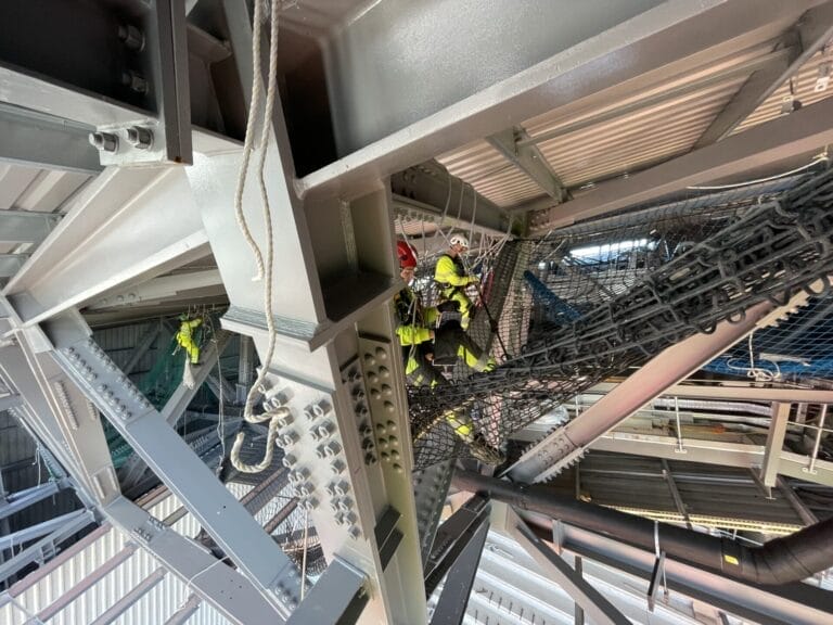 A group of workers are roofing a metal structure.