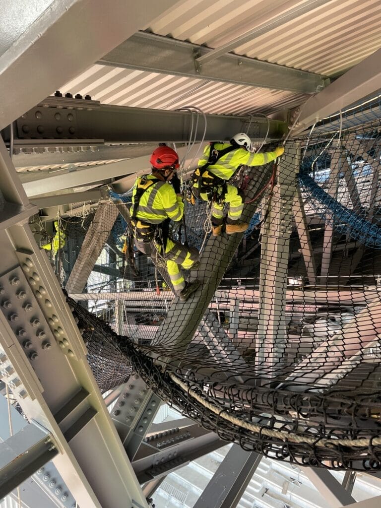 A group of workers are roofing a metal structure.