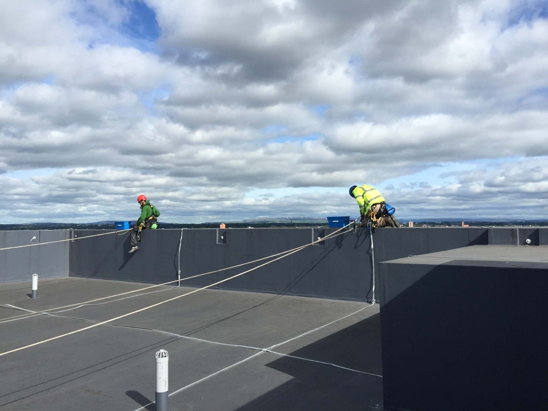 Two men performing building maintenance on the roof.