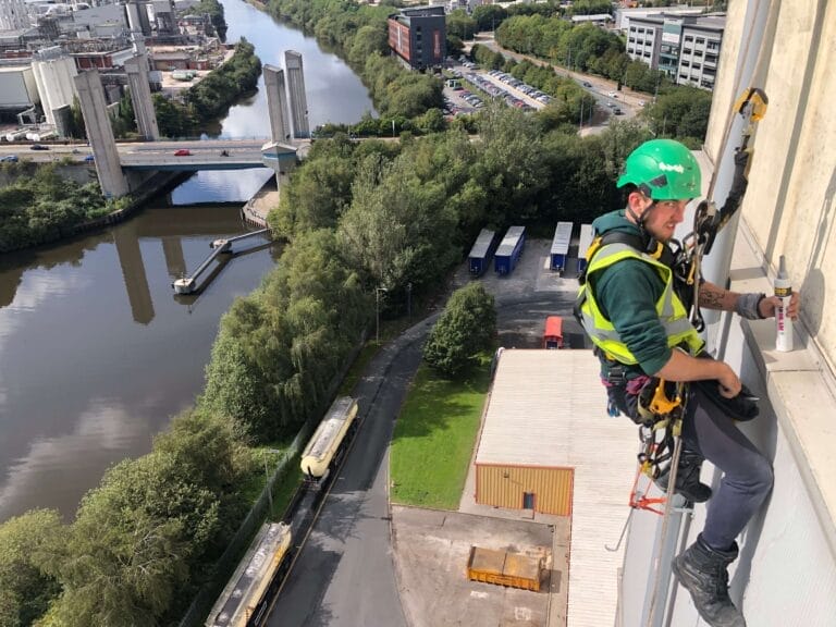 An electrician is climbing a tall building with a river in the background.