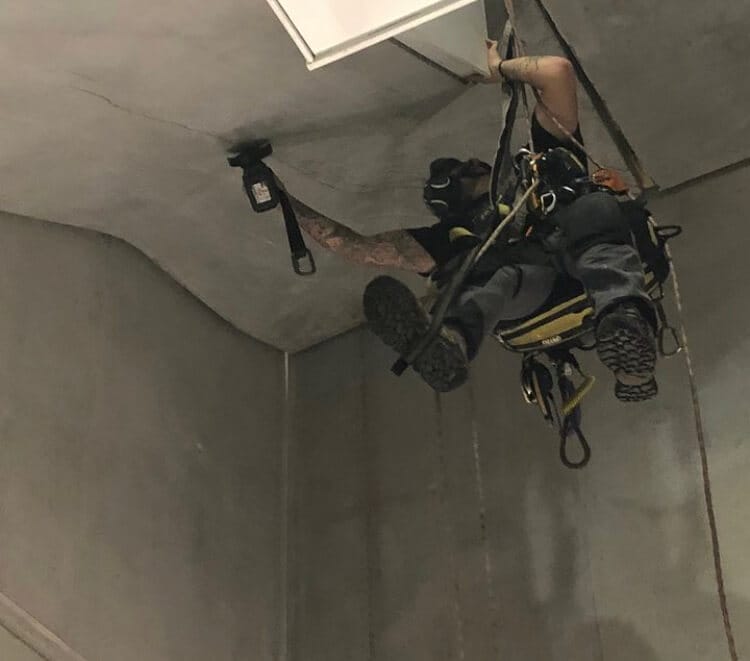 An electrician in a harness hanging from a ceiling.