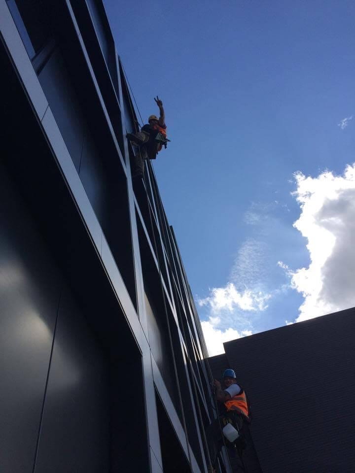 Two men ascending the facade of a building.