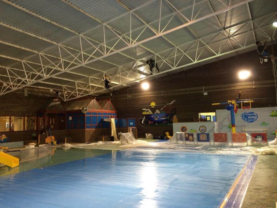 A large indoor swimming pool with a lot of equipment and vibrant painting.